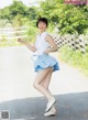 A woman in a white shirt and blue skirt is dancing.