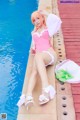 A woman in a pink bathing suit sitting by a pool.