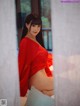 A woman in a red kimono sitting on a bed.