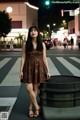 A woman standing in the middle of a street at night.