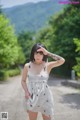 A woman in a white dress standing on a dirt road.