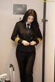 A woman in a black suit and tie standing in front of a door.