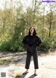 A woman standing in the middle of a dirt road.