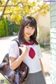 A woman in a school uniform holding a brown bag.