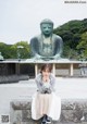 A woman sitting on a stone wall next to a statue.